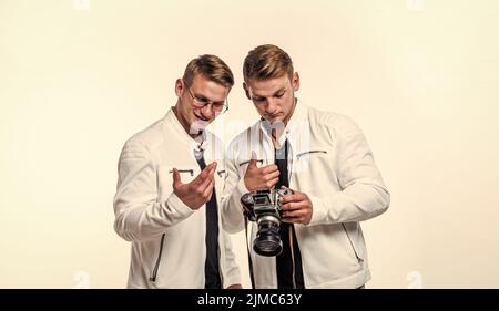 gli uomini gemelli dei fratelli osservano allo stesso modo usano la macchina fotografica vintage, fotografando Foto Stock
