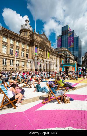 Una folla di spettatori che si godono il sole estivo in Victoria Square Birmingham guardando un grande schermo Commonwealth Games 2022 Foto Stock