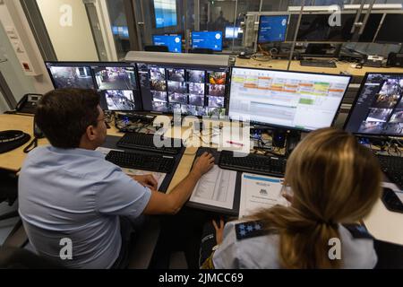 Friburgo, Germania. 05th ago 2022. Gli agenti di polizia si siedono di fronte al monitor di sorveglianza di diverse videocamere. La polizia di Friburgo ha installato una rete di telecamere in una zona molto frequentata di notte, che sono ormai in funzione da poco tempo. Credit: Philipp von Ditfurth/dpa - ATTENTION: Deployment data pixelated on the monitor/dpa/Alamy Live News Foto Stock