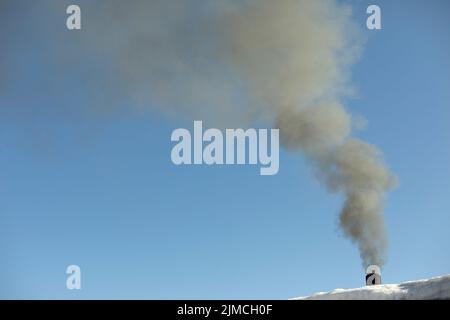 Fumo da camino. Fumo nel cielo. Riscaldamento domestico. Tubo sul tetto di casa. Foto Stock