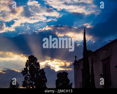 Il cambiamento sta venendo mentre il sole sbircia attraverso le nuvole in raggi di luce Foto Stock