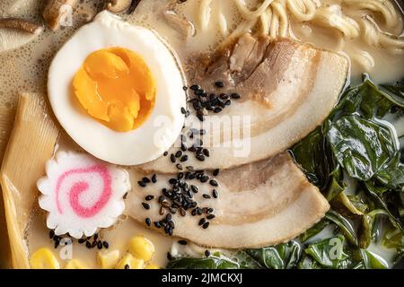 Primo piano di appetitosi ramen giapponesi con uova sode e funghi serviti in ciotola Foto Stock