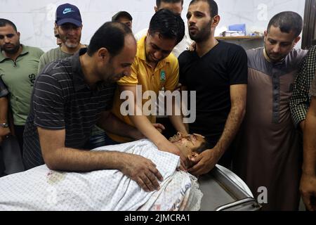 Gaza, Palestina. 5th ago 2022. Gli uomini palestinesi reagiscono di fronte al corpo di un uomo in un morgue ospedaliero a Khan Yunis nella striscia meridionale di Gaza dopo essere stati uccisi in uno sciopero aereo israeliano venerdì 5 agosto 2022. I mortali attacchi aerei dell'esercito israeliano a Gaza hanno ucciso 10 palestinesi e hanno ferito decine di testimoni. Foto di Ismael Mohamad/UPI Credit: UPI/Alamy Live News Foto Stock