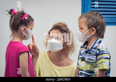 Famiglia indossare maschera facciale usa e getta. Protezione contro il coronavirus Foto Stock