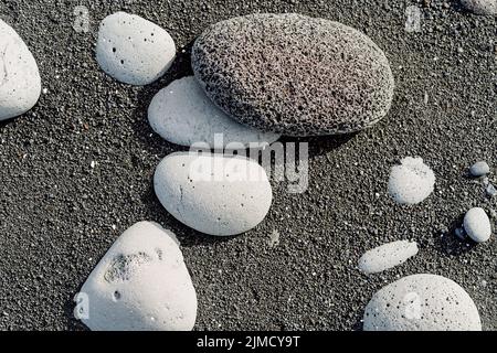 Vista dall'alto di pietre di varie forme e dimensioni sulla spiaggia di sabbia nera in una giornata di sole in Islanda Foto Stock