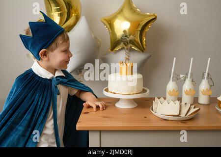 Ragazzo biondo con vista laterale che si prepara a soffiare le candele durante una festa di compleanno Foto Stock