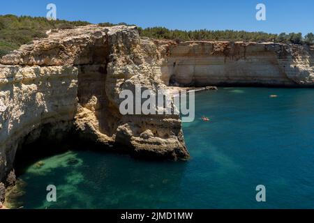 Da sopra spettacolare vista di persone anonime su una barca e kayak sotto il cielo blu in Algarve Portogallo Foto Stock