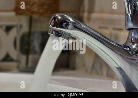 Chorro de agua cayendo de un grifo de un lavabo Foto Stock