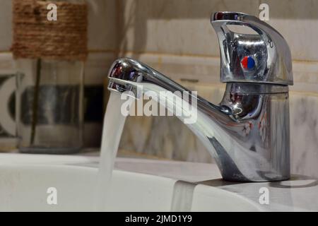 Chorro de agua cayendo de un grifo de un lavabo Foto Stock