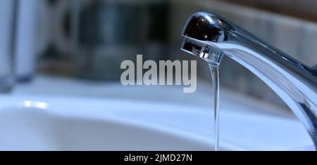 Pequeño chorro de agua cayendo de un grifo de un lavabo Foto Stock