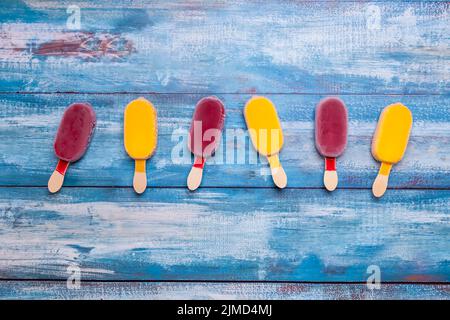 Bastone gelato posto su uno sfondo di legno vintage blu Foto Stock