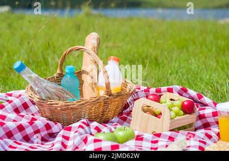 Grande concetto di pic-nic, pic-nic con frutta e succhi di frutta sul prato verde con bella vista Foto Stock