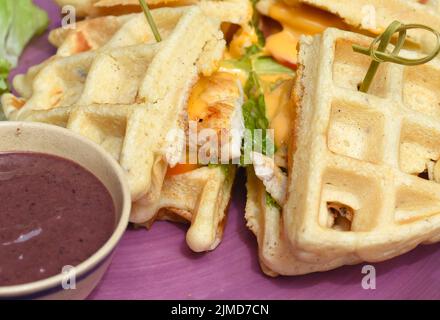 Waffle belgi con pollo fritto in padella su piastra porpora closeup Foto Stock