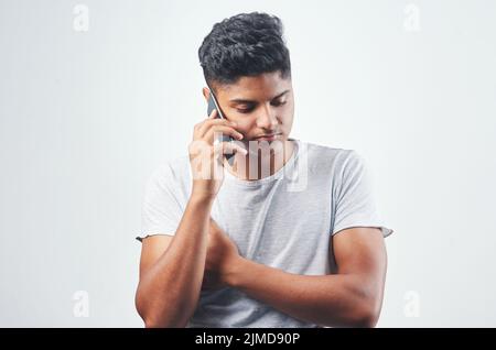 Lo shes non accetta ancora le mie chiamate. Studio girato di un giovane uomo che parla sul suo cellulare mentre in piedi su uno sfondo bianco. Foto Stock