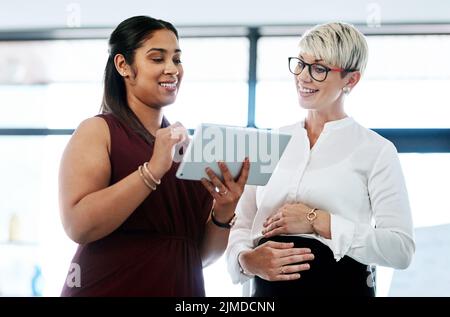 Lavorare insieme per raggiungere i loro obiettivi. Due donne d'affari che usano un tablet digitale insieme in un ufficio. Foto Stock