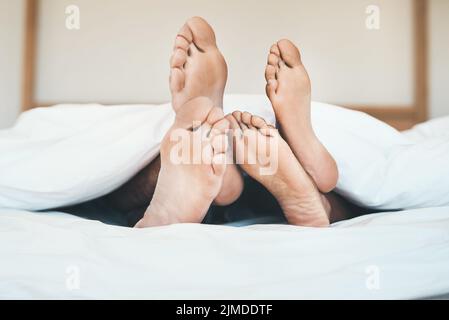 I piedi di una coppia innamorata che si trova a letto, rilassandosi e legandosi insieme a casa. Primo piano di un ragazzo a piedi nudi e ragazza che dormono, riposano o. Foto Stock