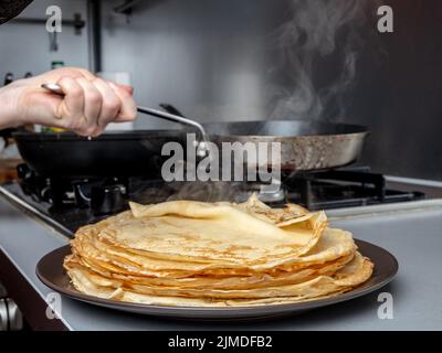 Frittelle appena sfornate impilate su un piatto da cui proviene il vapore. Trattamento tradizionale per le vacanze della settimana di Pancake. Foto Stock