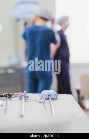 Strumenti medici sterili sul tavolo della sala operatoria. Chirurghi su uno sfondo molto sfocato Foto Stock