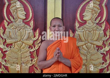 Un monaco buddista a Wat Mongkon (Mongkol) Nimit nella città di Phuket, Phuket, Thailandia, accoglie il visitatore con un wai, il tradizionale saluto tailandese Foto Stock