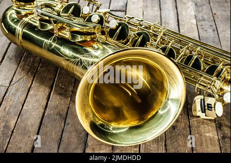 Pezzo di sassofono giallo - campana e valvole su una superficie di legno d'annata Foto Stock