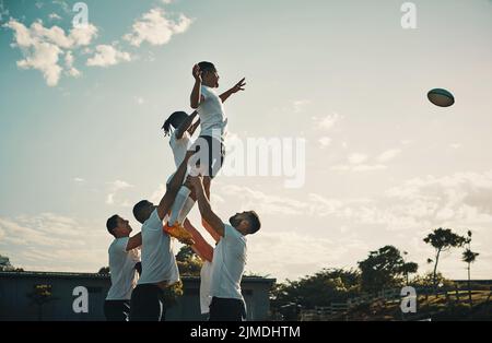 È solo una questione di millisecondi prima che lo catturasse. Un bel giovane giocatore di rugby che cattura la palla durante un allineamento sul campo. Foto Stock