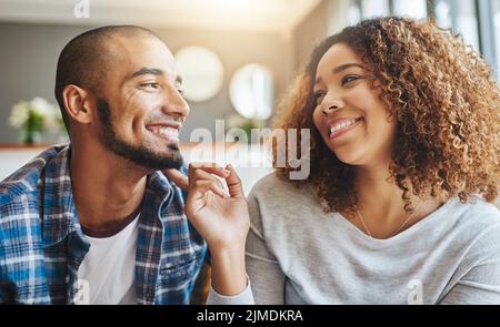 Primo piano di una giovane coppia felice che si lega ed è affettuoso mentre si rilassa insieme a casa. Ragazzo sorridente e ragazza appeso fuori e. Foto Stock