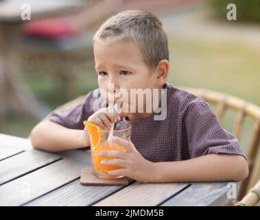 Un ragazzo che mangia un gelato nella caffetteria all'aperto Foto Stock