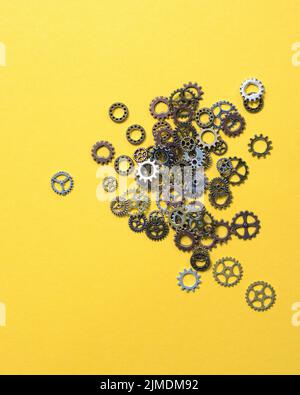 Ruote dentate in ottone di diverse dimensioni giacenti su sfondo giallo. Concetto di sviluppo e soluzioni. Foto Stock