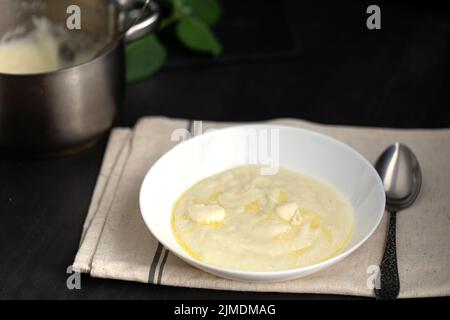 Porridge di semola in ciotola bianca su tavolo di legno scuro. Foto Stock