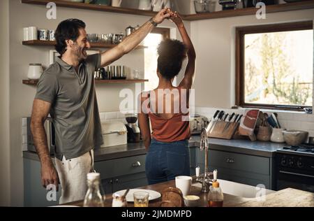Felice, romantica e interrazziale coppia ballare e divertirsi mentre si legano in cucina a casa. Spensierata ed energica coppia amorosa che si sente allegra Foto Stock