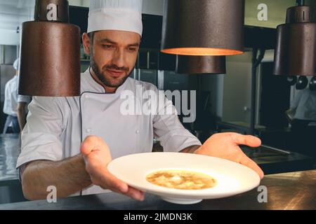 Lo chef professionista controlla il piatto appena prima di servirlo al cliente nel ristorante Foto Stock
