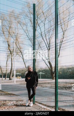 Felice giovane donna che tiene il telefono cellulare sul campo da basket Foto Stock