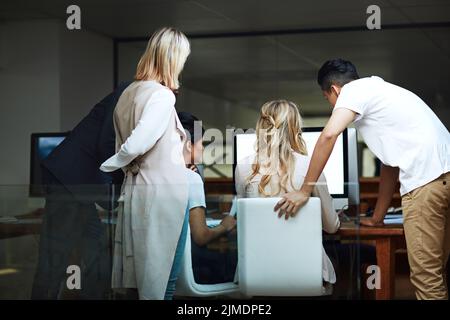 Team di colleghi che pianificano, discutono e condividono idee mentre lavorano su un computer in un ufficio aziendale. Vista posteriore di un gruppo di designer Foto Stock