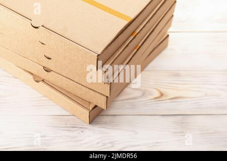 Servizio di consegna cibo. Ordine pizza è confezionato in scatole marrone, stack, vista dall'alto su tavolo di legno Foto Stock