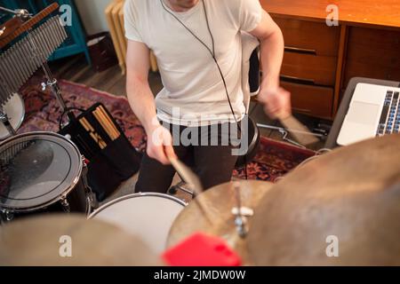 Il giovane uomo suona la batteria in primo piano in casa studio. Foto Stock