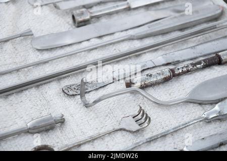 set di vecchi strumenti medici morsetti, bisturi e forbici su sfondo bianco, pratica medica Foto Stock