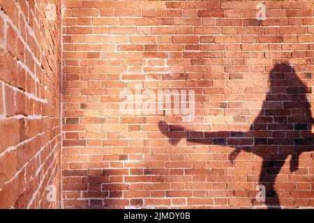 Ombra di un uomo su un muro di mattoni sfondo Foto Stock