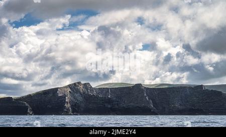 Alte scogliere di Kerry con un cielo spettacolare, viste da una barca sull'Oceano Atlantico Foto Stock