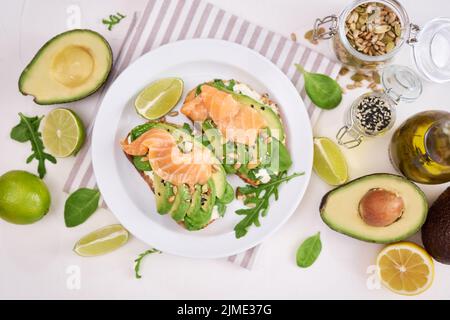 Avocado appena fatto, salmone e formaggio cremoso toast su un piatto di ceramica bianca Foto Stock