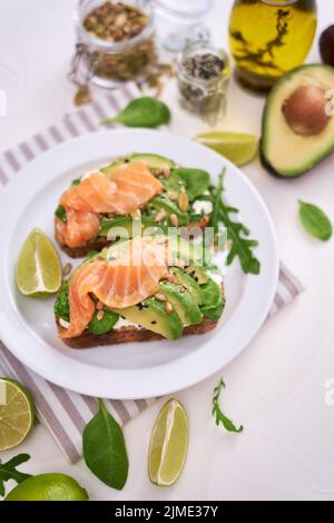 Avocado appena fatto, salmone e formaggio cremoso toast su un piatto di ceramica bianca Foto Stock