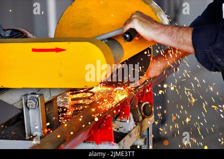 Taglio di metalli in officina presso il sito di produzione con una macchina fissa. Sega circolare elettrica per metallo. Foto Stock
