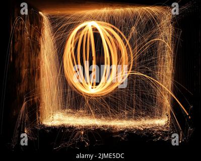 Lana d'acciaio che gira in un tunnel, gettando scintille gialle e arancioni facendo un disegno di filatura Foto Stock