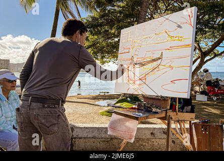 Honolulu, Hawaii - 6 novembre 2021-Man dimostra la pittura su una spiaggia en plein air. Foto Stock