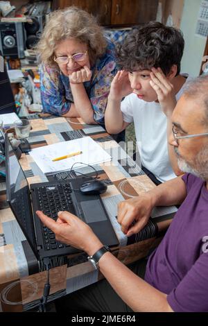 Nipote che viene insegnato dai suoi nonni è divertito di fronte a laptop a casa Foto Stock