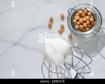 Chickpea aquafaba montata sulla frusta del miscelatore planetario Foto Stock