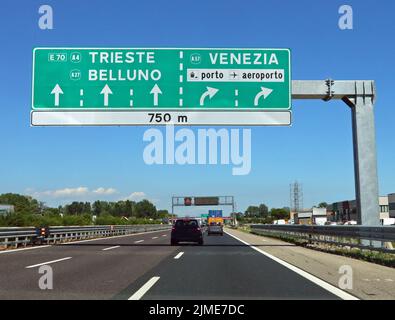 Svincolo autostradale con grande cartello con indicazioni per le principali città italiane come Venezia e l'aeroporto Foto Stock