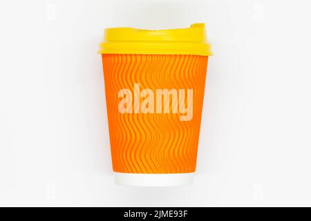 Tazza da caffè di carta. Tazza da caffè in carta arancione con coperchio in plastica gialla. Tazza usa e getta per bere bevande calde e fredde in tutta sicurezza. Capacità nervata sicura Foto Stock