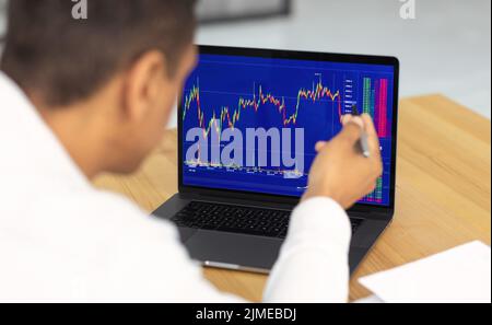 Il giovane commerciante di borsa African American analizza il mercato che funziona in ufficio Foto Stock