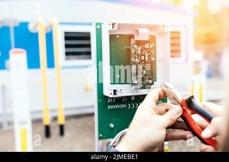 Regolazione dell'apparecchiatura di controllo e misurazione. Le mani di un elettricista o di un ingegnere con pinze in primo piano. Foto Stock