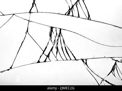 Numerose incrinature nel vetro che si sono frantumate sul parabrezza della vettura. Concetto di vetro incrinato su sfondo bianco per desi Foto Stock